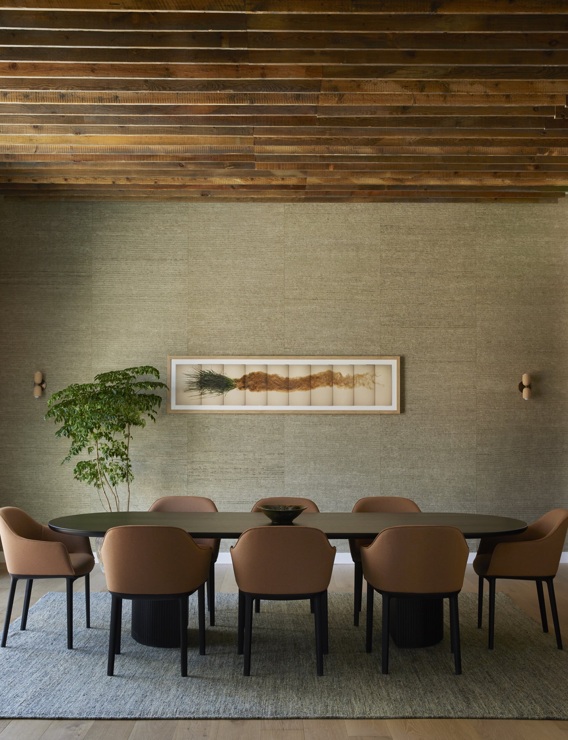 A view of the Enclave, a private meeting room with a long table, leather chairs, and a horizontal artwork on a gray wall.