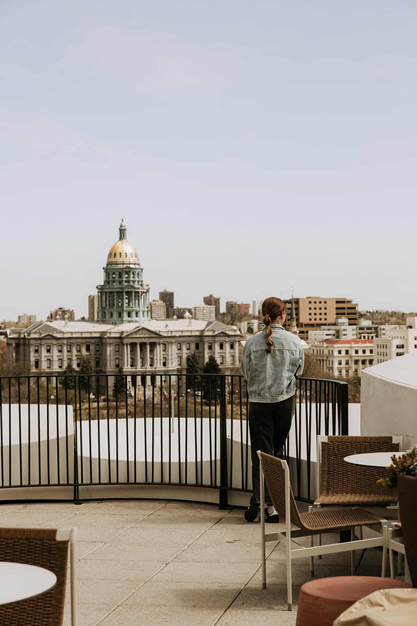 Guest standing on the Populus rooftop overlooking the Colorado State Capitol’s gold dome and downtown Denver.