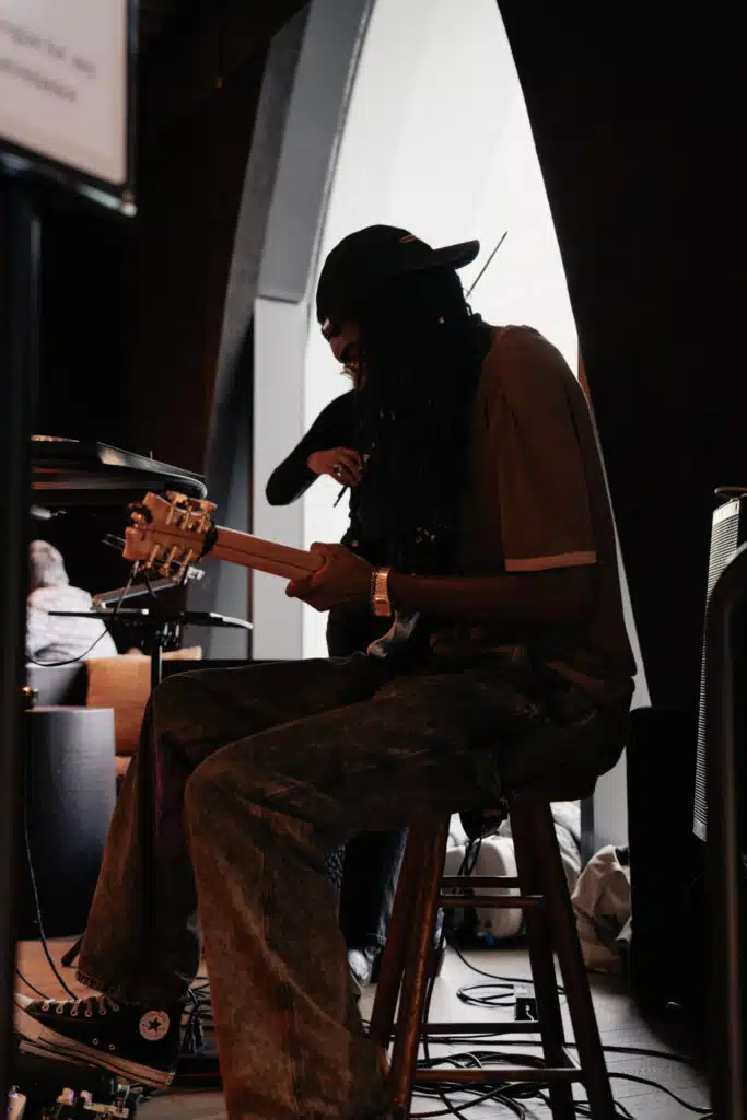A silhouette of a guitarist backlit by a curved window at Populus