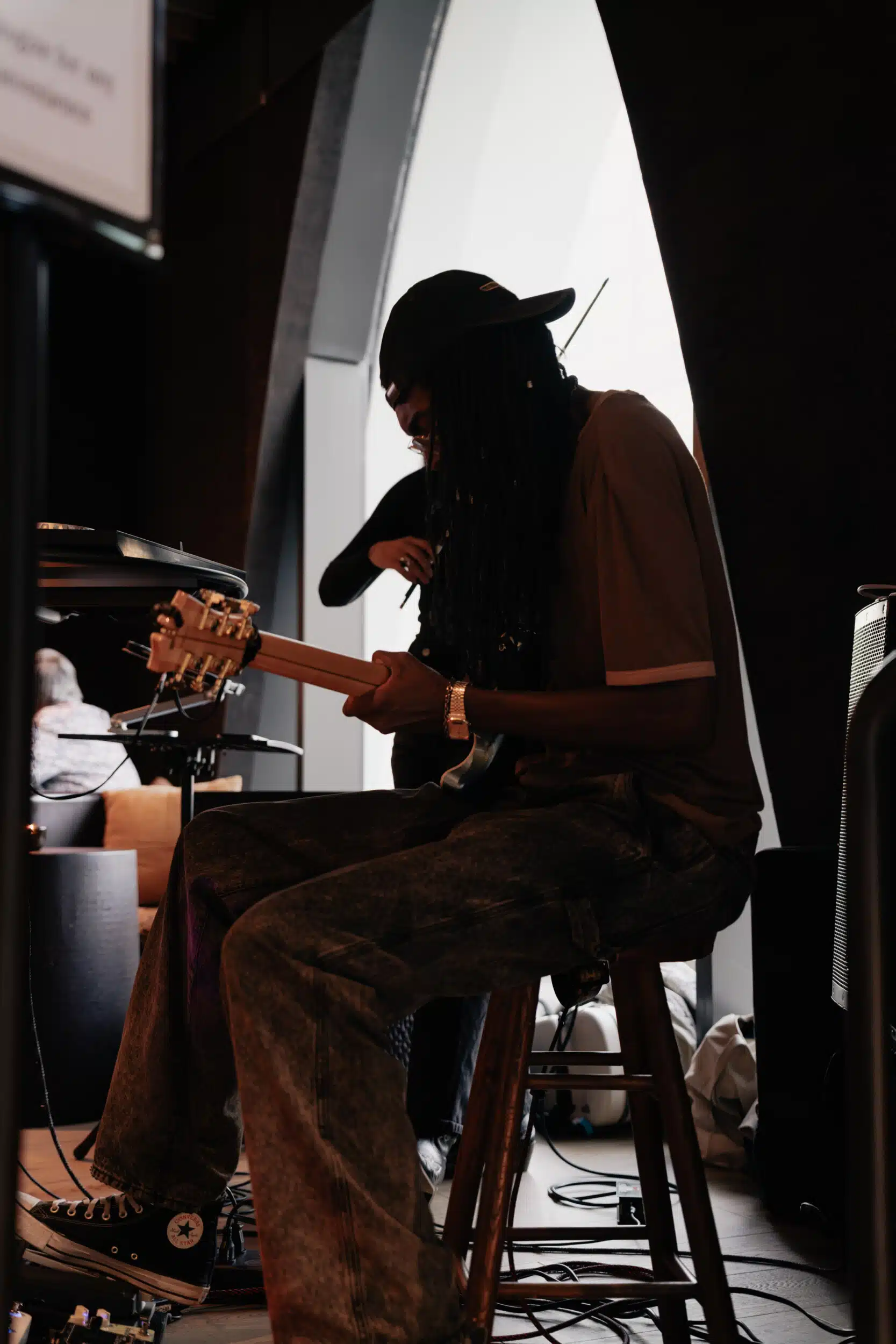 A silhouette of a guitarist backlit by a curved window at Populus