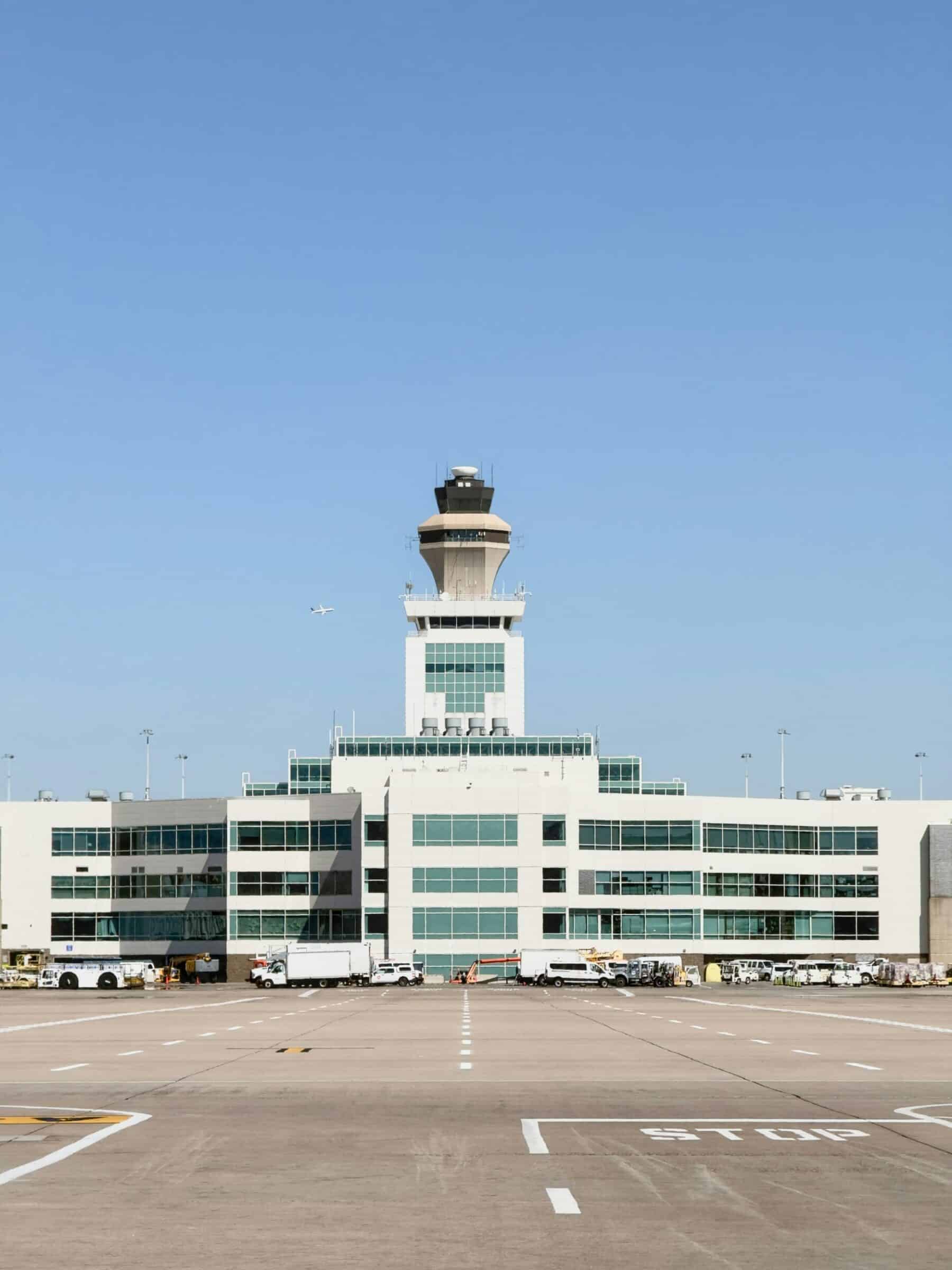 Denver International Airport terminal building with a control tower against a clear blue sky.