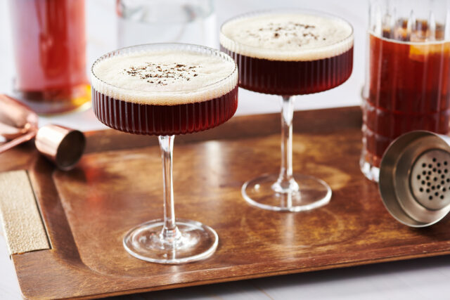 Two espresso martini cocktails on wood tray