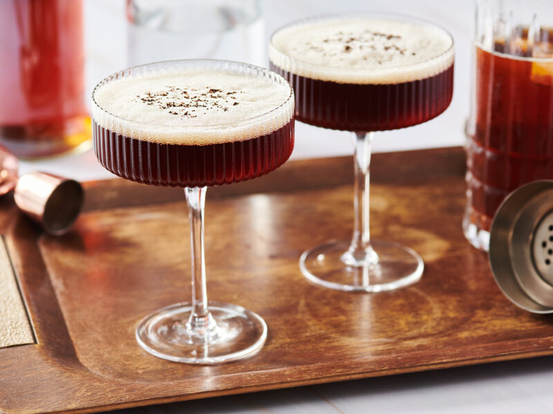 Two espresso martini cocktails on wood tray
